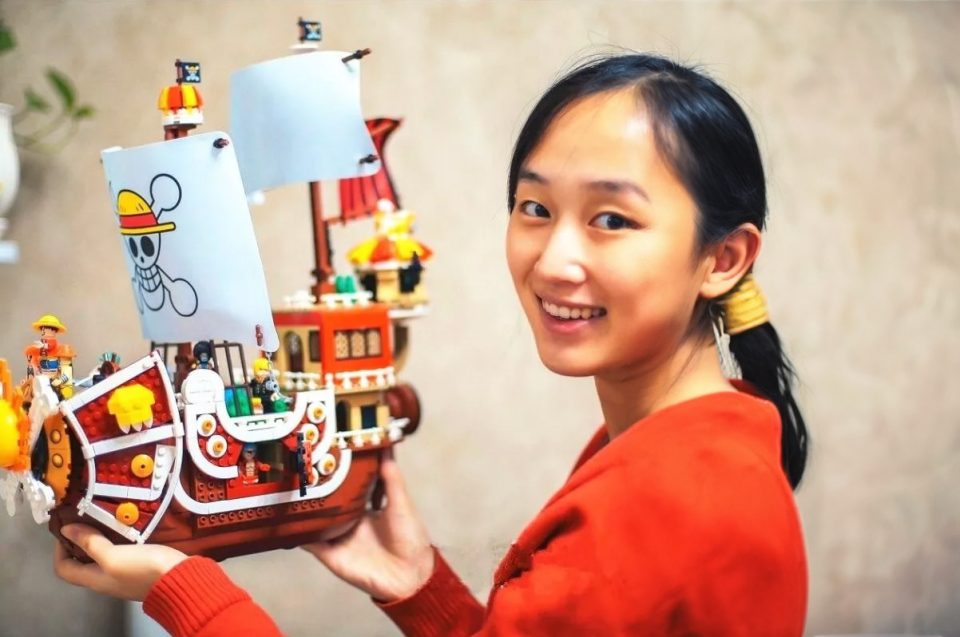 Girl holding a imitation LEGO Thousand Sunny ship from One Piece